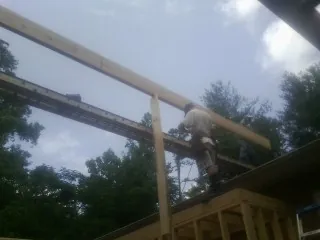 Carpenter setting a ridge beam over a new addition frame — Ice Dam Removal by Roofing Brothers in Ionia