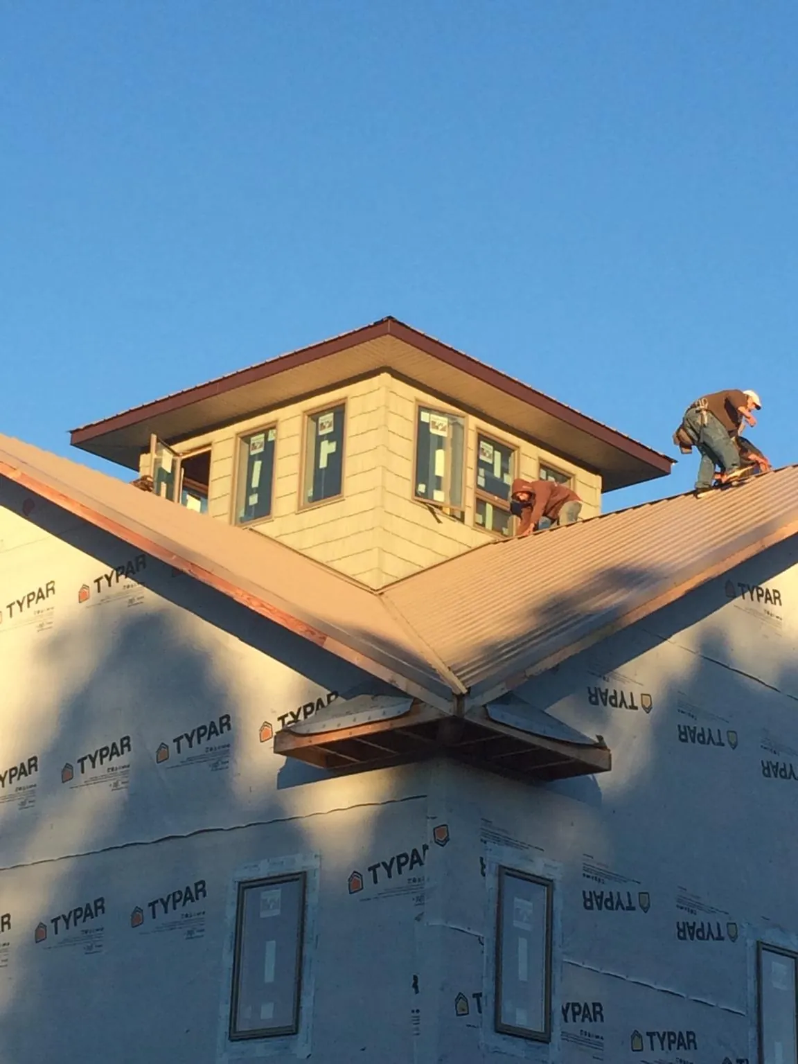 Roofers working around a rooftop cupola on a new metal roof at sunset — Roof Waterproofing in Ionia by Roofing Brothers